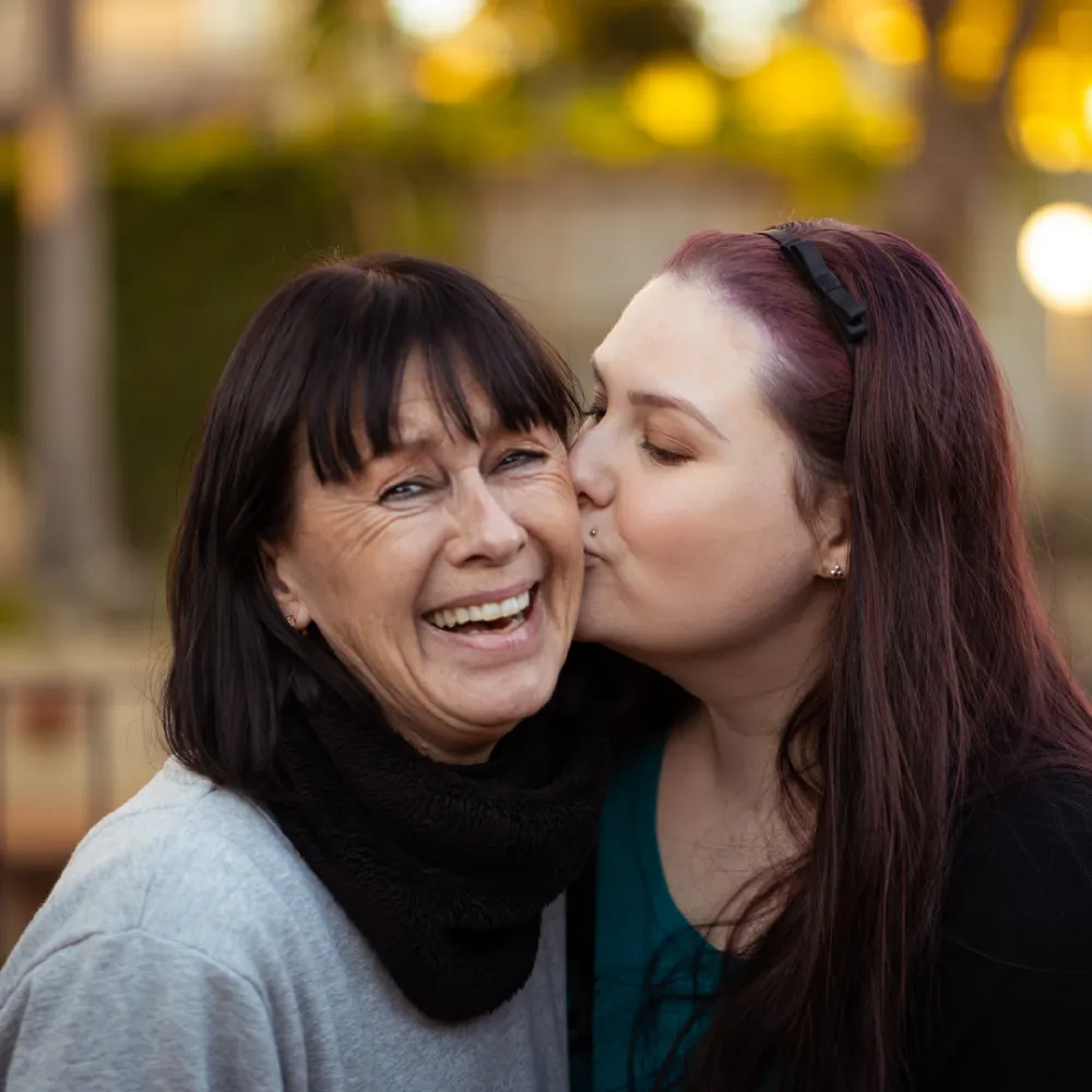 Image of a young woman kissing an older woman on the cheek
