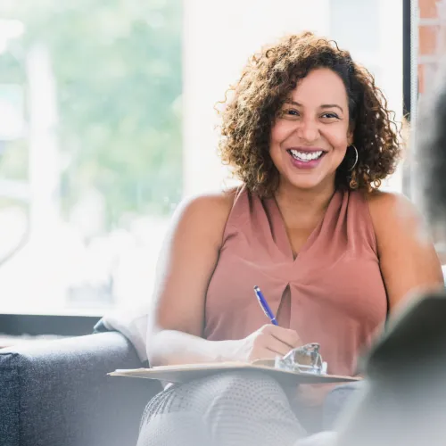 Seated smiling woman writing on clipboard