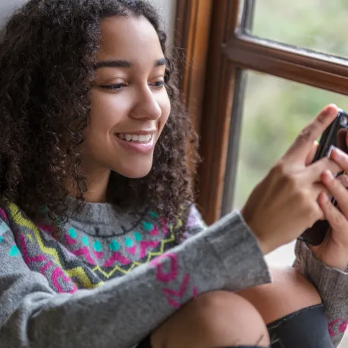 Image of young woman smiling while viewing mobile phone