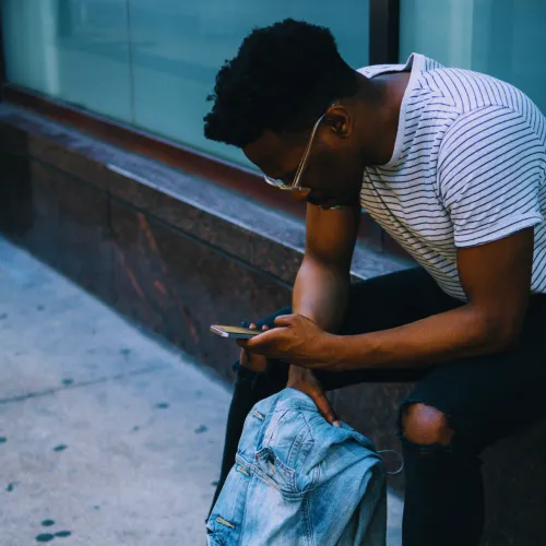 Young man seated typing on mobile phone