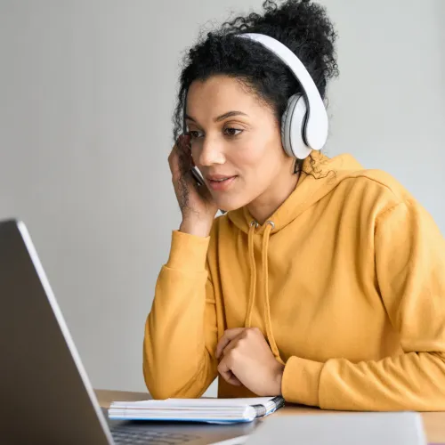Picture of a young woman wearing headphones working at a laptop